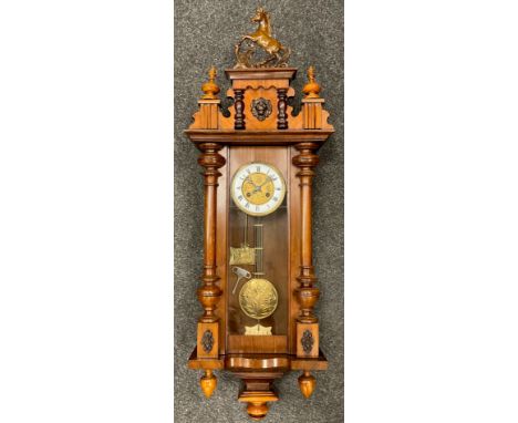 A mahogany cased Vienna ‘Astor’ wall clock, ‘carved’ horse cresting, brass dial with white enamel chapter ring, black Roman n