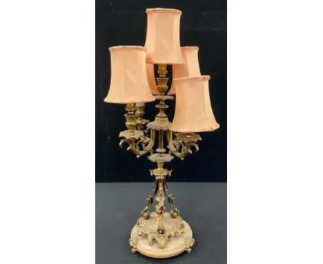 A gilt metal five light table lamp, as a candelabra, with central taller light, surrounded by four floral scrolling arms, tri