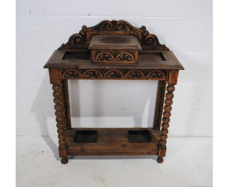 A turn of the century oak hall stand, with central storage compartment with lift up lid, with carved decoration and bobbin tu