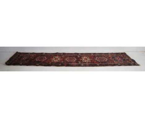 A hand-woven red ground Eastern runner - 347cm x 85cm