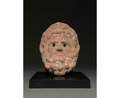 600-900 BC. Etruscan. Terracotta mask of a male figure with long hair and full beard; the hairs are depicted in a stylised ma