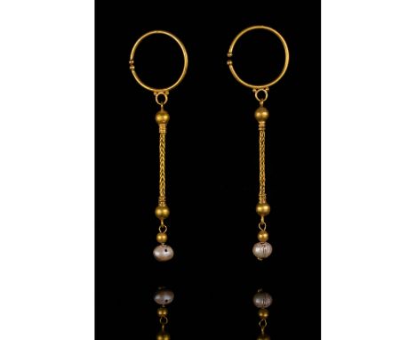 c. 100-300 AD. Roman. A pair of gold hoop earrings each with a single elongated pendant comprising a spherical bauble attache