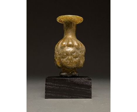 100-300 AD. Roman. Yellowish-green glass flask with in-folded, flaring rim, cylindrical neck, mould-blown Janus-head body com