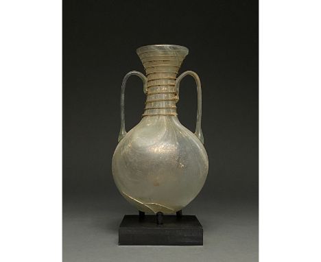 Possibly Grand Tour period. Roman-style yellowish-green glass vessel with a flaring neck, tapering rim, globular body and app