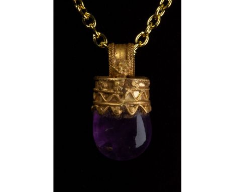c. 323-31 BC. Greek Hellenistic period. A gold pendant with a circular, ribbed suspension loop, cylindrical body and amethyst