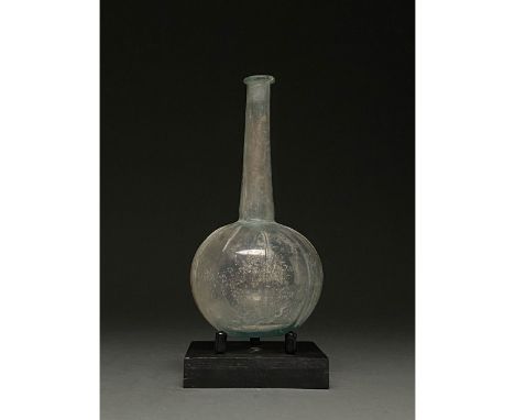 100-300 AD. Roman. Pale blue glass vessel with folded rim, elongated, flaring neck and globular body. Now weathered with a gu