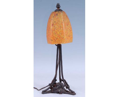 A French Art Deco iron desk lamp, having a hexagonal slightly domed orange mottled glass shade, raised on triform leaf decora