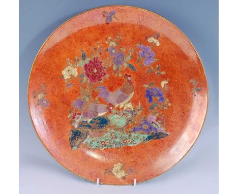 A 1930s Carltonware ceramic charger, the unusual burnished orange ground decorated with standing cockerels within stylised fo