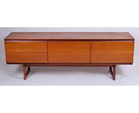 A 1960s teak long sideboard by White &amp; Newton Ltd, having fall-front central compartment flanked by single cupboard door 