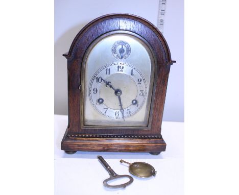 A vintage oak cased mantle clock with pendulum and key 