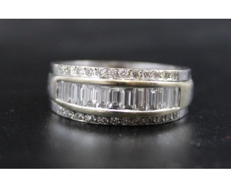 An 18ct white gold half eternity ring, incorporating a row of 13 baguette cut diamonds, flanked by two outer rows of (in tota