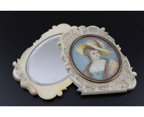 A 19th century carved ivory pocket mirror, the rotating cover fitted with an oval miniature portrait painting, a lady in feat