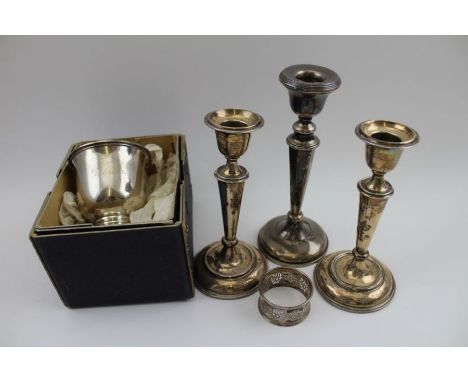 A pair of silver candlesticks, Birmingham 1910, a single silver candlestick, a pierced silver napkin ring, and a silver one h