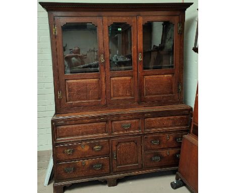 A mid 18th century oak country made dresser/press cupboard with moulded and dentil cornice, the upper section with 3 part gla