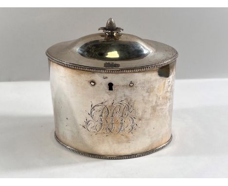 A late 18th century plain oval silver tea caddy, domed top with pineapple finial, beaded borders, fitted lock, London, 1784, 
