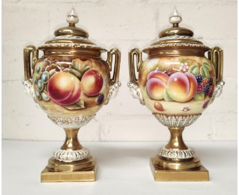 A pair of Royal Worcester two handled lidded urns, 'Hand Painted Study of Fruit', decorated with peaches, berries, grapes etc