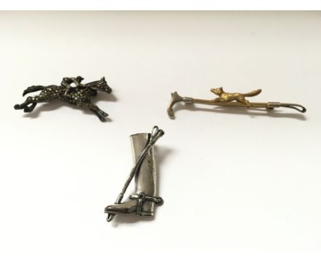 A 9ct gold two tone hunting tie pin. One other white metal ridding boot and a silver horse racing brooch.