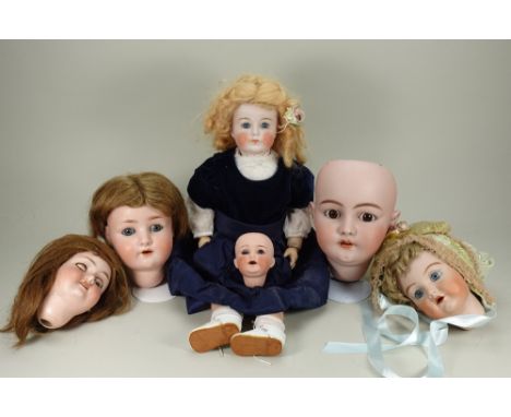 Four bisque dolls heads, German circa 1915, including an A.M 390 with weighted blue glass eyes and brown wig, incised A5M, sm