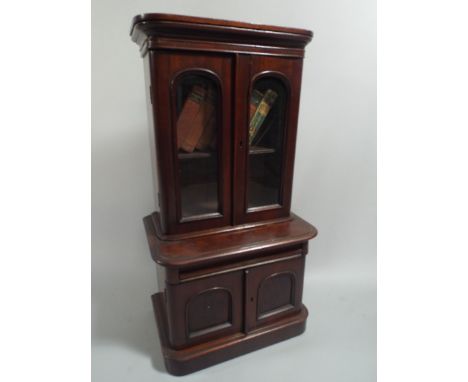 A Victorian Mahogany Miniature Bookcase in the Apprentice Style. Panelled Doors to Base Cupboard and Glazed Bookcase with Sin