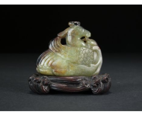 A Chinese green and russet jade carving of a phoenix, Qing Dynasty, carved nestling amid a fruiting peach branch, with carved