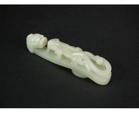 A Chinese pale greenish-white jade belt hook, late Qing Dynasty, carved with a dragon's head forming the hook, facing an unde