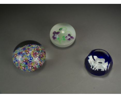 Three Baccarat paperweights, including a millefiori example dated 1972, an example decorated with with a purple flower and a 