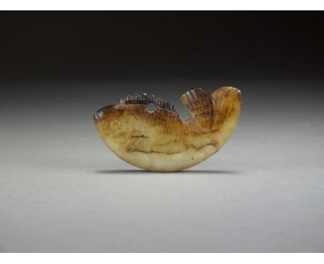 A Chinese pale green and brown jade fish pendant, possibly Ming Dynasty, modelled as a carp, 8cm longProvenance: Receipt from