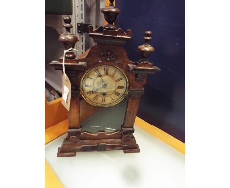 An oak and pine bracket clock with brass bezel and Roman numerals, surmounted with ribbon bows, swags and finial