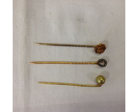 THREE YELLOW METAL STICK PINS, A PEARL, A HORSE SHOE AND A FLOWER 