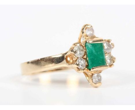 A gold, emerald and diamond ring, mounted with the cut cornered rectangular step cut emerald within a surround of six circula