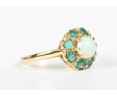 A gold, opal and emerald cluster ring, claw set with the circular opal within a surround of eight circular cut emeralds, deta