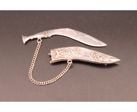 A white metal brooch in the form of a kukri knife, the knife being removable from its scabbard, 6.5 cm 8.3 g