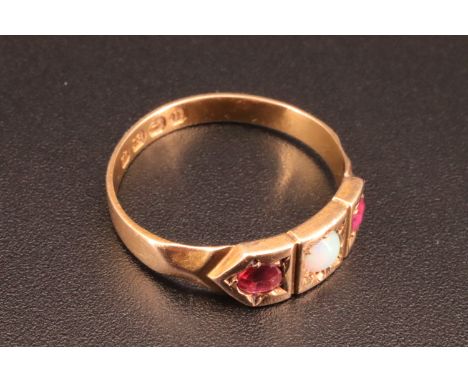 An Edwardian 18 ct ruby and opal ring, having three geometric panels with an opal cabochon set between two rubies, the shank 