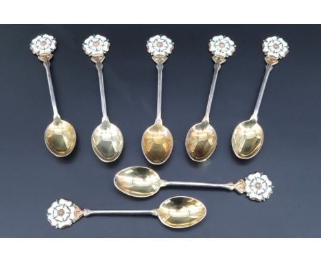 Seven 1960s enamelled silver coffee spoons, having a white and green enamel and parcel gilt York rose terminal, and gilt bowl