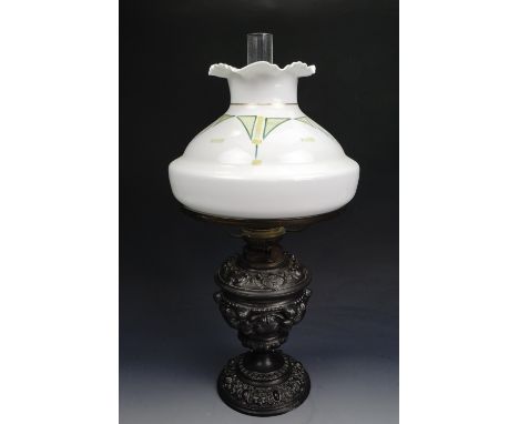 An antique German Kosmos Brenner Baroque style base metal oil lamp, the base incorporating winged cherubim, with a Secessioni