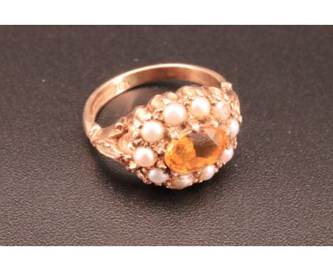 A 9 ct gold citrine and seed pearl ring, having a central oval citrine surrounded by 10 claw set seed pearls and shoulders de