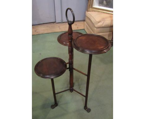 In the manner of Liberty &amp; Co an Arts &amp; Crafts mahogany three tier cake stand the brass ring handle on a turned colum