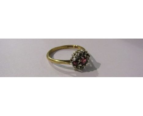 A 9ct gold ring set with three rubies enclosed by six individually set diamonds. Size O/P, 2.4g 