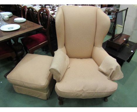 A wingback armchair in silk upholstery with carved front legs and matching pouffe 