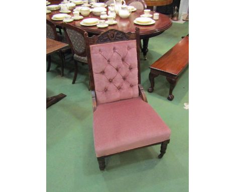 An Edwardian walnut button back open armchair with carved decoration over turned legs and ceramic castors   