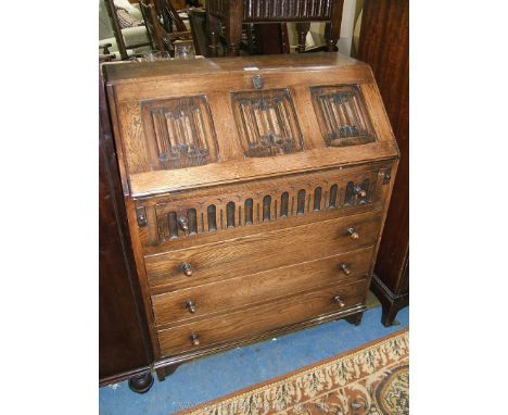 A reproduction Oak Priory style Bureau with plain top, the fall having three linen fold carved panels opening to reveal eight