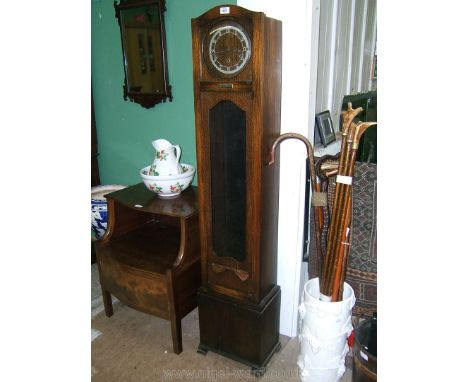 An early 20th c. Oak Grandmother Clock, dome top with long two pane door and circular upper pane opening to reveal the applie