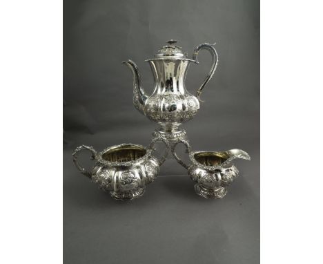 A silver three piece coffee service comprising coffee pot, sucrier and cream jug, embossed floral design, monogrammed, London