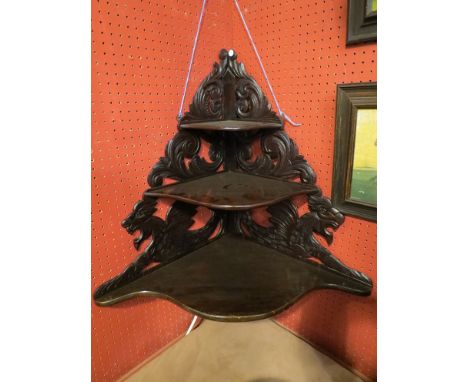 A 19th Century mahogany three tier corner shelf with scroll acanthus leaf and griffin carving