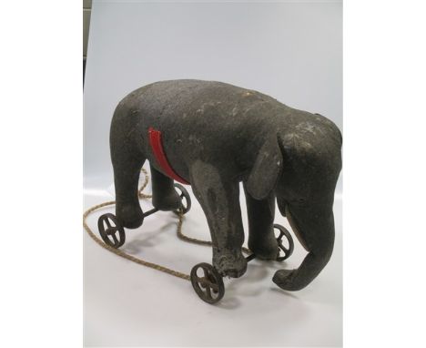 A large Steiff elephant on wheels, grey felt with white felt tusks, remnants of the red and gold felt saddle strap, Steiff bu