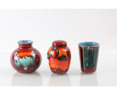 Three pieces of Poole pottery to include a small lidded jar, all in vibrant colour