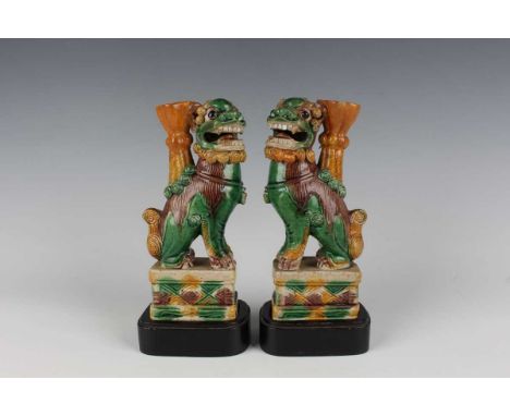 A pair of Chinese sancai enamelled biscuit porcelain Buddhistic lion jostick holders, Kangxi period, each modelled seated on 