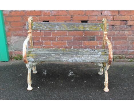 A CAST IRON FRAMED 19TH CENTURY GARDEN BENCH, the plank seat and back supported on twin cast ends each with mask head detail,