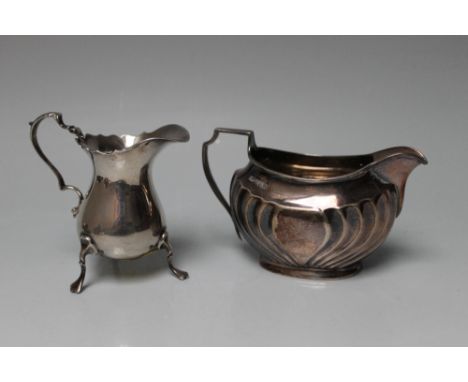 TWO MODERN HALLMARKED SILVER CREAM JUGS, the first having a fluted design - Sheffield 1928 and the second having a shaped rim