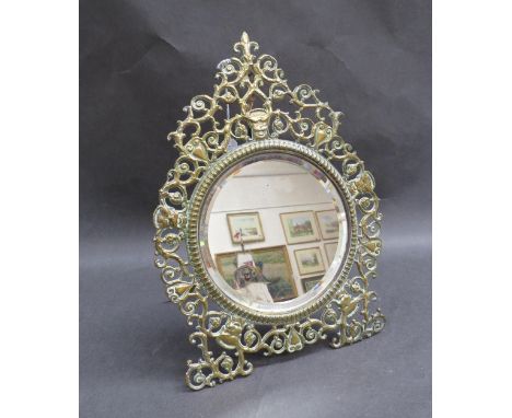A circular bevel edged easel backed mirror in ornate pierced brass frame, 33cm x 22cm 